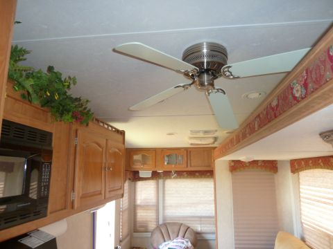 1992 Ford Mustang - Camper interior wood cabinets, a microwave, and a ceiling fan overhead.