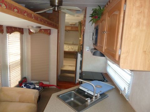 1992 Ford Mustang - The interior of a recreational vehicle shows a living area, kitchen sink, and a bedroom accessible via stairs.