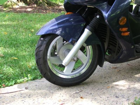 2008 Yamaha Zuma - Close-up of a scooter's front wheel and fender assembly, showing the tire and suspension components.