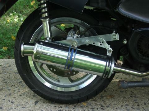 2008 Yamaha Zuma - Close-up view of a scooter's chrome exhaust system and rear wheel assembly.