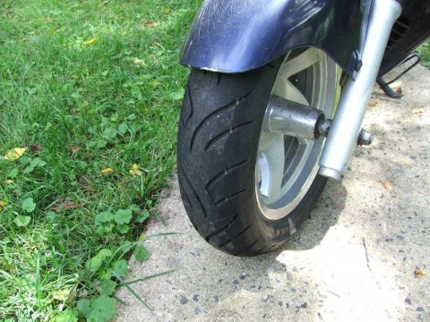 2008 Yamaha Zuma - Close-up of a scooter's front wheel and fender, showing the tire and part of the suspension.