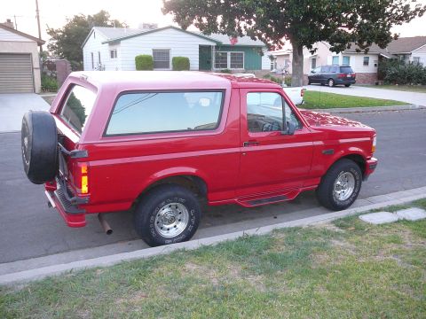 1988 Ford Bronco - This red Ford Bronco features a spare tire mounted on the rear door and appears to be from the early to mid-1990s.
