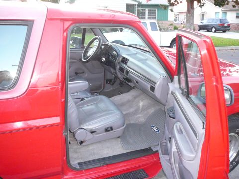 1988 Ford Bronco - Interior of a red Ford Bronco, showing the driver's seat and dashboard area.