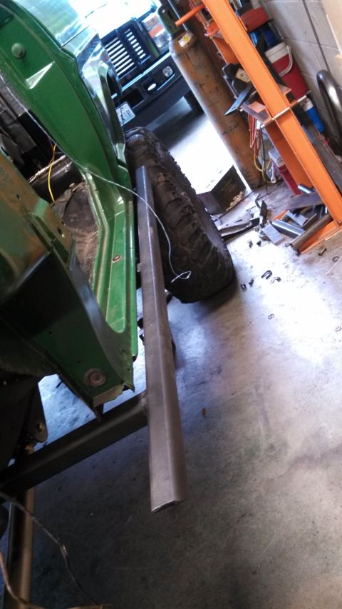 1967 Ford F-250 - A green 1967 Ford F-250 cab is shown from the side, with a large tire and metal bar in the foreground and another truck in the background.