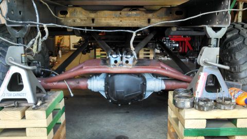 1967 Ford F-250 - The underside of a truck is visible, supported by jack stands, with the differential and suspension system prominently displayed.