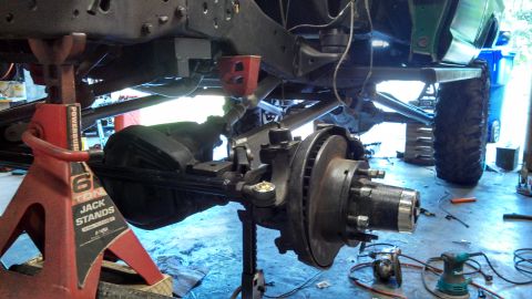 1967 Ford F-250 - Close-up view of the front axle and suspension of a truck undergoing maintenance in a garage.