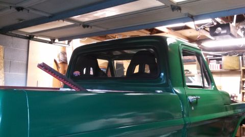 1967 Ford F-250 - The rear interior of a green 1967 Ford F-250 pickup truck shows racing seats and a sticker on the rear window.