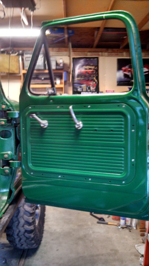1967 Ford F-250 - Interior view of a 1967 Ford F-250 door, showing the green panel and hardware. A tire is visible below.