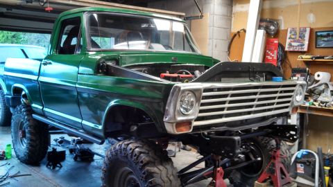 1967 Ford F-250 - A green pickup truck is undergoing maintenance in a garage, with its front end raised on jack stands.