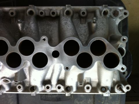 1992 Ford Bronco - Close-up of an aluminum intake manifold, likely for a V8 engine. Text 'SUPERMOTORS' is visible.