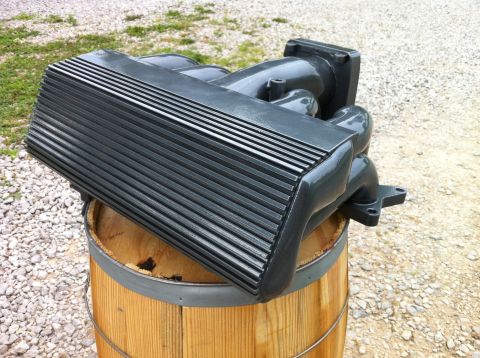 1992 Ford Bronco - An intake manifold rests on a wooden barrel outdoors, with a gravel and grass background.