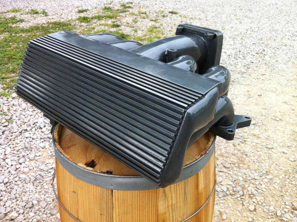 Dark gray intake manifold on a wooden barrel, angled view