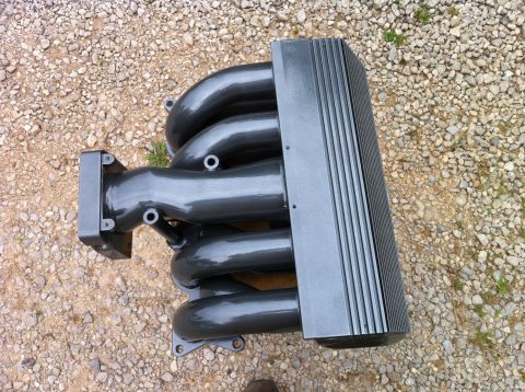 1992 Ford Bronco - A gray intake manifold with four runners and a ribbed cover is shown on a gravel surface.
