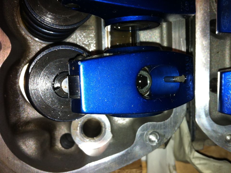 Close-up of blue roller rocker arm and valve spring assembly in an engine