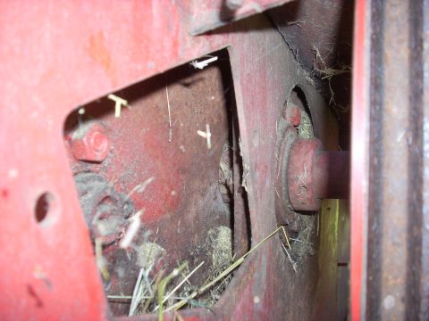 1963 Hummer H3 - Close-up view of the interior workings of a red agricultural machine, showing hay debris and various metal parts.
