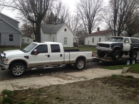 1996 Ford Bronco - A lifted two-tone Ford Bronco is transported on a trailer behind a modern pickup truck.