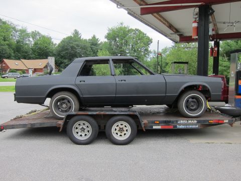1991 Ford LTD Crown Victoria - Unfinished sedan body being transported on a trailer.