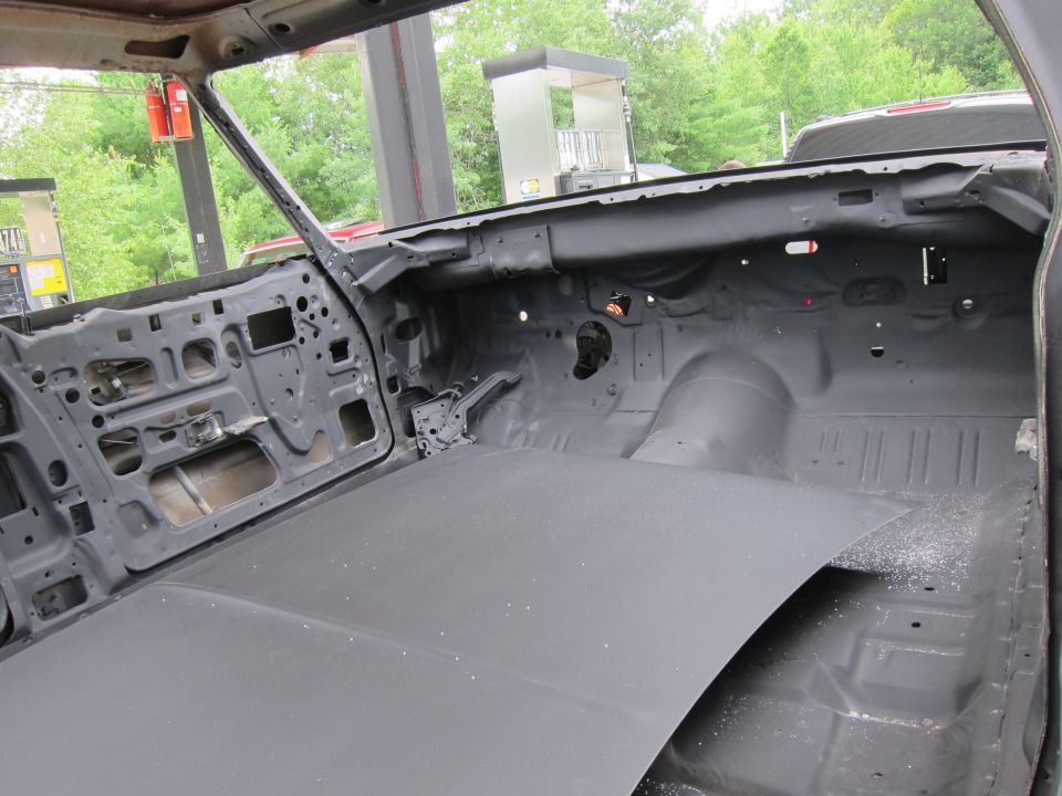 Car interior stripped down to metal, showing door panels and floor