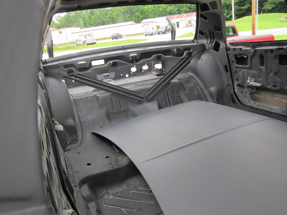 Interior of a car stripped down for restoration, showing bare metal and primer