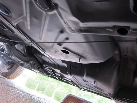 1991 Ford LTD Crown Victoria - The undercarriage of a vehicle is visible, with a focus on the fuel tank and structural components.
