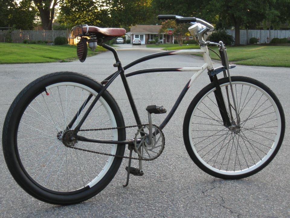 Black and white bicycle with a brown leather seat and a grenade-shaped taillight