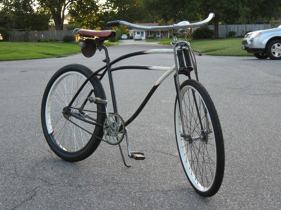 Custom cruiser bicycle with a brown leather seat and chrome handlebars parked on a suburban street