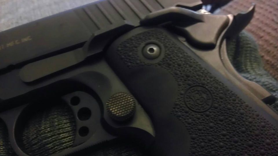 Close-up of a black pistol grip with textured panels and a circular emblem