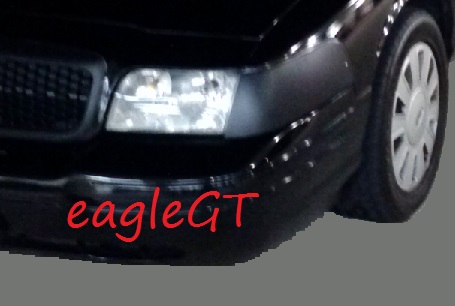 2008 Ford Crown Victoria - The front corner of a black car is shown, a headlight and wheel.