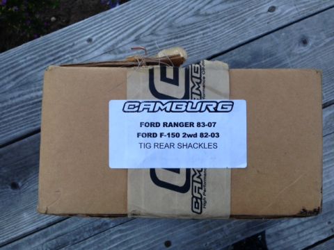 1986 Ford Bronco - A cardboard box containing automotive parts sits on a wooden surface.