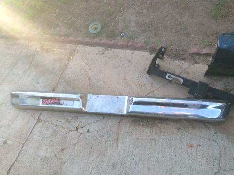 1986 Ford Bronco - A chrome bumper with a 'DARE' sticker is shown on the ground next to some other vehicle parts.