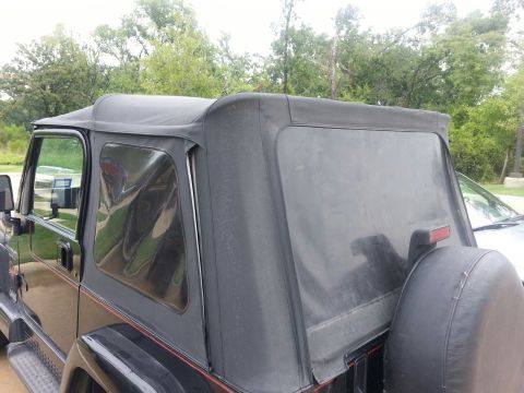 1986 Ford Bronco - This Jeep Wrangler features a black soft top and a spare tire mounted on the rear.