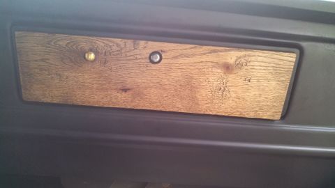 1979 Ford Bronco - Close-up of a wood grain trim panel with two knobs on a dark dashboard.