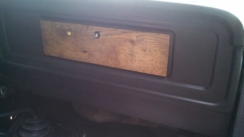 1979 Ford Bronco - Close-up of a vehicle's interior dashboard, showing a faux woodgrain accent panel.