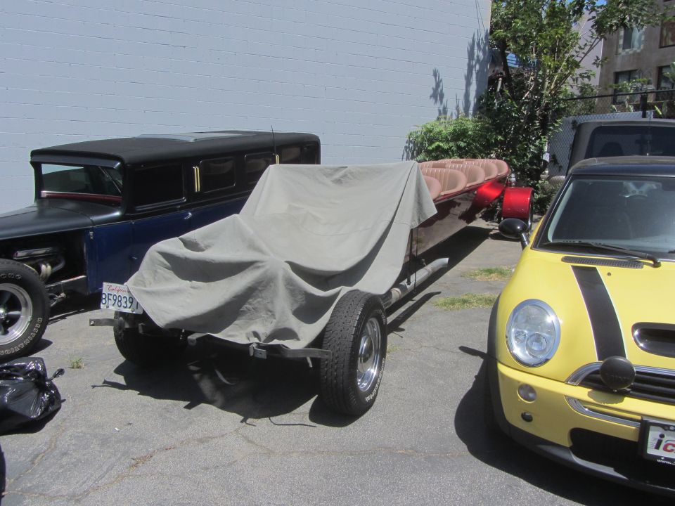 Trailer covered with tarp, parked next to a blue hot rod and a yellow Mini Cooper