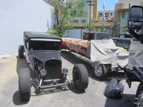 1968 Ford Mustang - A custom hot rod is parked next to a trailer loaded with red seats, with other vehicles visible in the background.