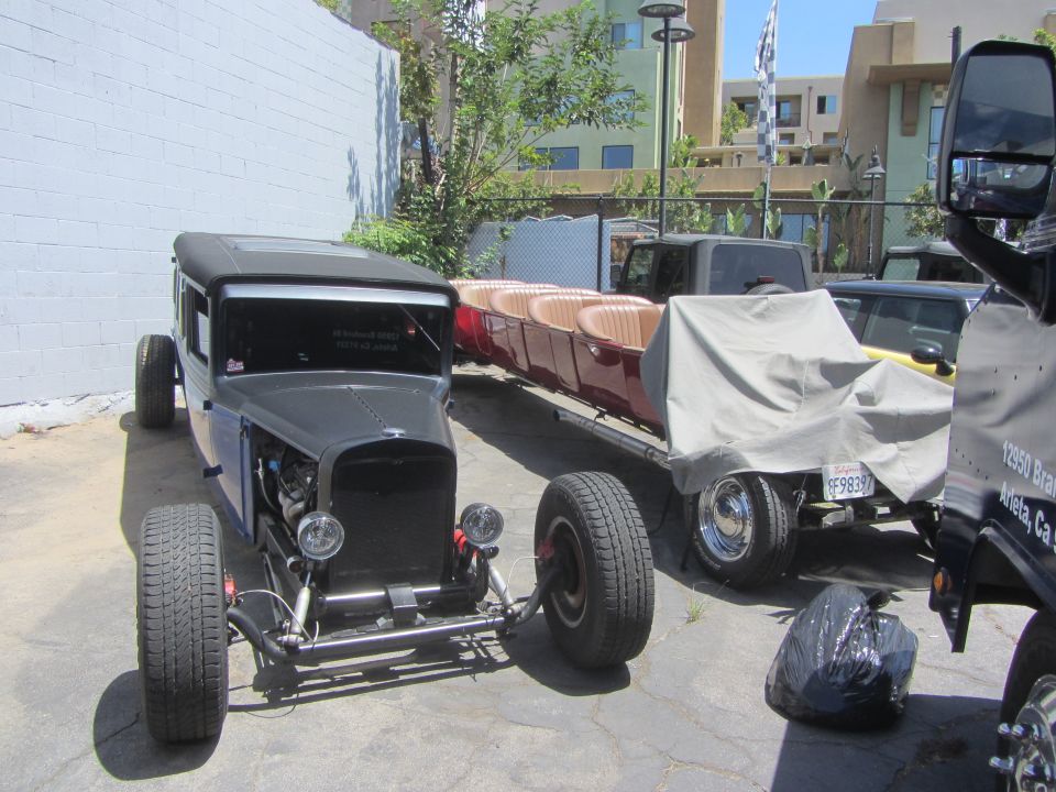 Hot rod with exposed engine and a trailer carrying red seats