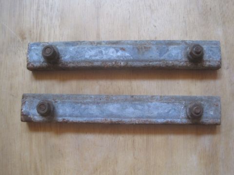 1993 Ford Bronco - Two metal brackets with bolts are shown against a wooden background.
