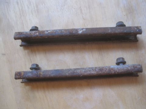 1993 Ford Bronco - Pair of rusty metal brackets with bolts, likely for automotive use.