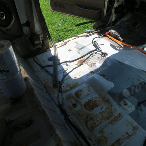 1995 Ford Bronco - The interior of a vehicle is shown stripped down, revealing rusted floor pans and exposed wiring.