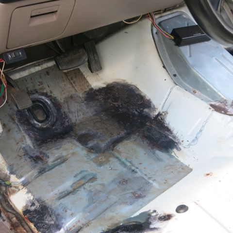1995 Ford Bronco - The interior floor of a vehicle shows pedals and an aftermarket amplifier, with evidence of rust and repair.