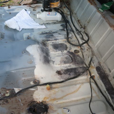 1995 Ford Bronco - The interior floor of a vehicle is shown with rust and exposed wiring, indicating a need for restoration.