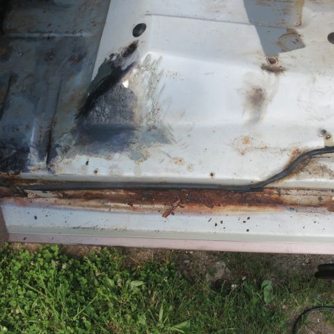 1995 Ford Bronco - Close-up of a vehicle's interior floor showing significant rust along the rocker panel.