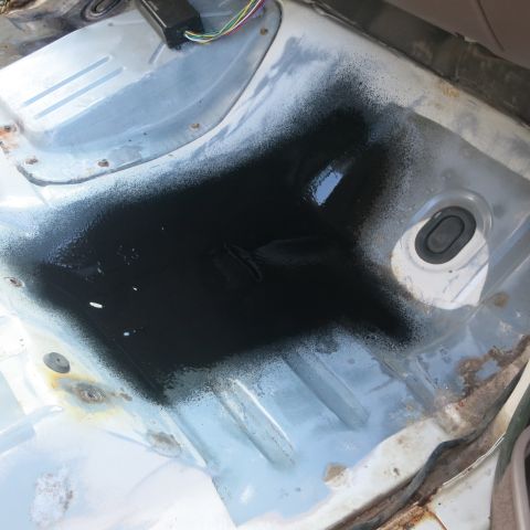 1995 Ford Bronco - The interior floor pan of a vehicle shows signs of recent black spray paint application.