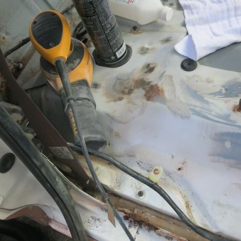 1995 Ford Bronco - Tools and a towel are placed on the rusty interior of a vehicle.