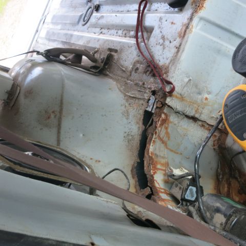 1995 Ford Bronco - The interior floor pan of a vehicle shows significant rust damage and structural compromise.