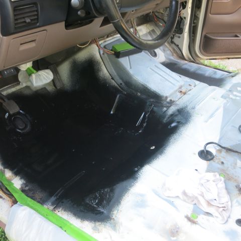 1995 Ford Bronco - The floor of a vehicle's interior is being coated with black paint during a restoration project.