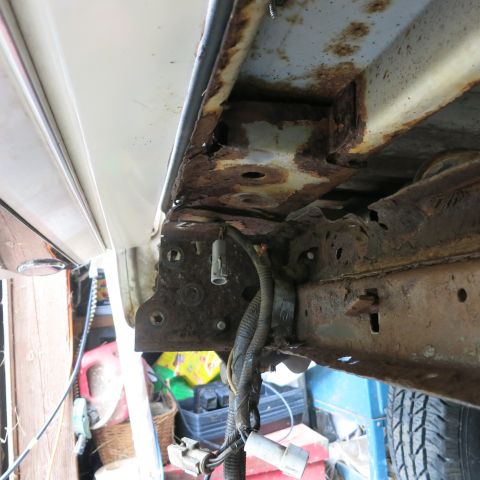 1995 Ford Bronco - The undercarriage of a vehicle shows significant rust damage on the frame and body panels.