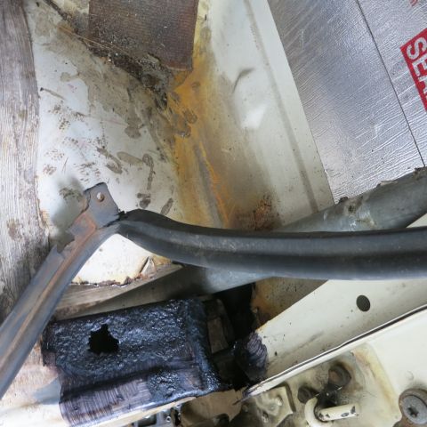 1995 Ford Bronco - The vehicle's undercarriage displays extensive rust and damage, with a broken bracket and sealant applied sealant.
