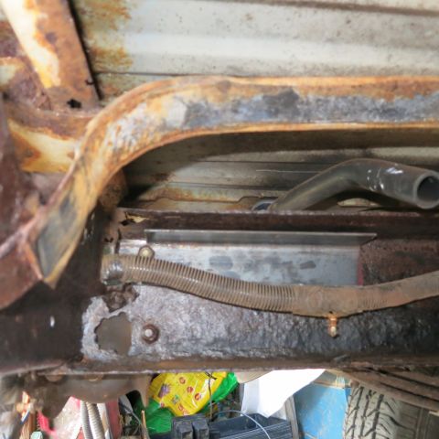 1995 Ford Bronco - The underbody of a vehicle shows significant rust and damage to its frame and components.