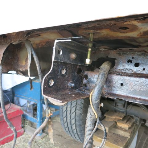 1995 Ford Bronco - Close-up view of a frame bracket and wiring harness attached to a rusty vehicle chassis, with a tire visible in the background.